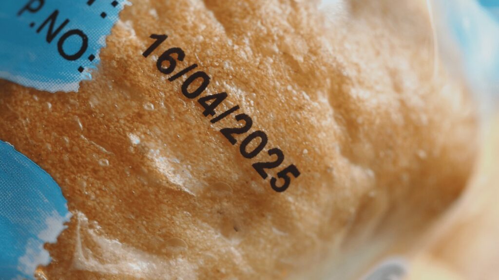 Gros plan sur une date de péremption imprimée sur un emballage alimentaire, illustrant la question des dates et du gaspillage alimentaire.